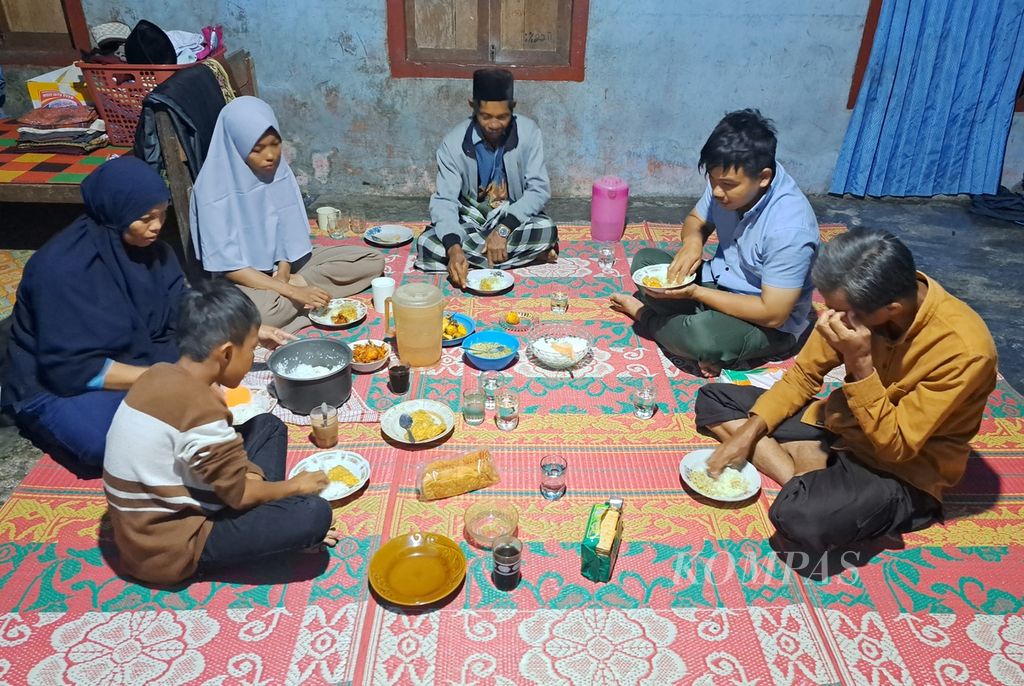 Keluarga Karemanto (44) dan Lisnayenti (41) sedang santap sahur dengan menu sederhana dan penerangan dari listrik genset di rumah, Kampung Langgai, Nagari Ganting Mudiak Utara Surantih, Kecamatan Sutera, Kabupaten Pesisir Selatan, Sumatera Barat, Kamis (14/3/2024).