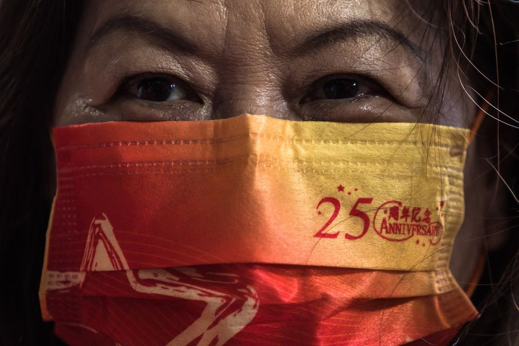 Seorang perempuan mengenakan masker dengan logo perayaan 25 tahun penyerahan Hong Kong dari Inggris kepada China, 1 Juli 2022 di Hong Kong. 