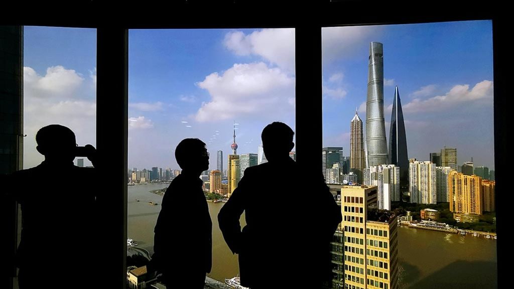 Beberapa orang berdiri di dekat jendela yang mengarah ke area pusat keuangan di Shanghai, China, 23 Oktober 2019. 