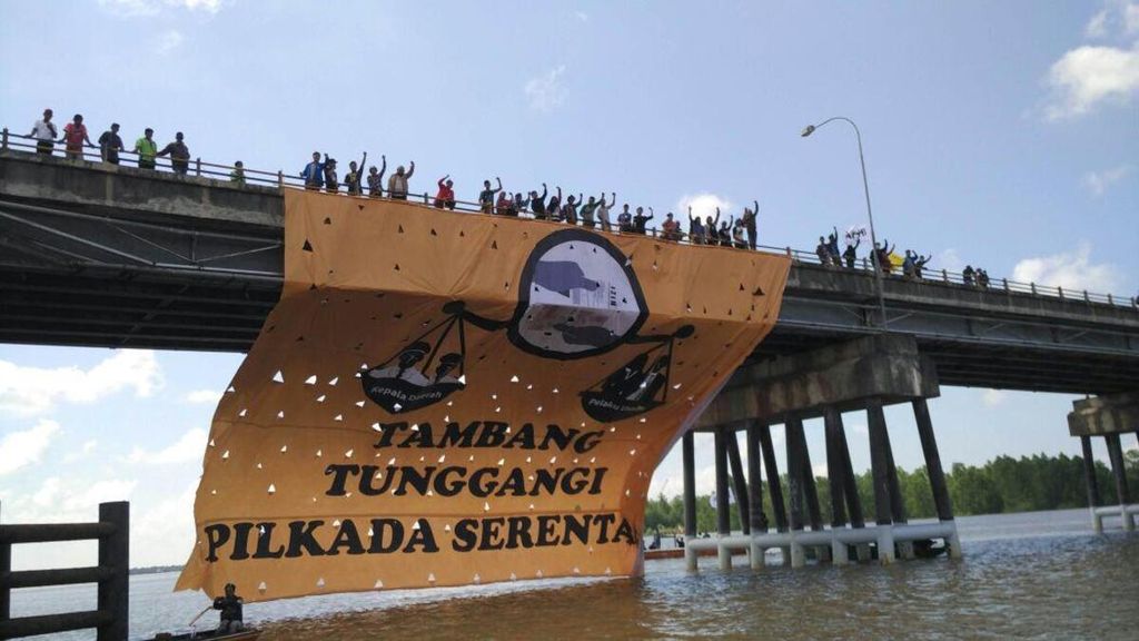 Koalisi Antimafia Tambang dan Sawit menggelar aksi menentang kebijakan pemerintah yang terus tergantung pada batubara dan sawit. Mereka membentangkan spanduk raksasa di Sungai Dondang, salah satu jalur kapal tongkang batubara di Kutai Kartanegara, Kaltim, Sabtu (5/5/2018).