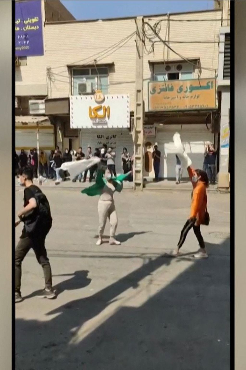 Foto yang diambil dari potongan video UGC yang diunggah secara daring, Jumat (30/9/2022), ini memperlihatkan perempuan Iran mengibarkan penutup kepala mereka dalam unjuk rasa di sebuah ruas jalan di kota Ahvaz, Iran barat laut. 