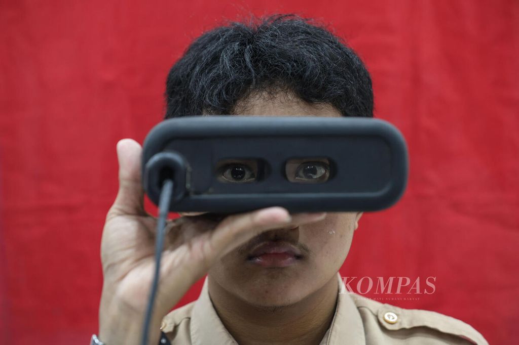 Petugas dinas kependudukan dan pencatatan sipil (dukcapil) memasangkan alat perekam retina mata ke mata salah seorang siswi yang mengikuti perekaman KTP elektronik di SMAN 38 Jakarta, Rabu (7/2/2024). 