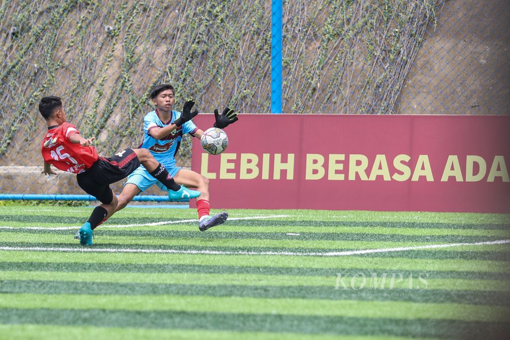 Penjaga gawang Bina Taruna, Sundiego Moses Sitanggang (biru), menahan bola yang ditendang pemain M-Private, Alvaro Wirasena, dalam babak utama Liga Kompas Kacang Garuda U-14 di Dewantara Sport Center, Tangerang Selatan, Banten, Minggu (26/11/2023). 