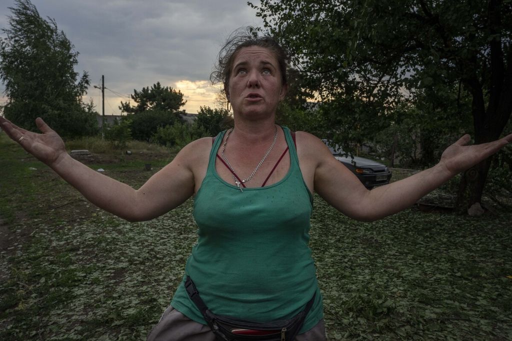  Tetiana Pashko (43) berdiri di depan bangunan rumahnya yang rusak di Pokrovsk, timur Ukraina , Sabtu (16/7/2022). Taktik bumi hangus yang tampaknya dilancarkan oleh militer Rusia membuat banyak warga bertanya tentang masa depannya pascaperang yang belum jelas kapan akan berakhir. 