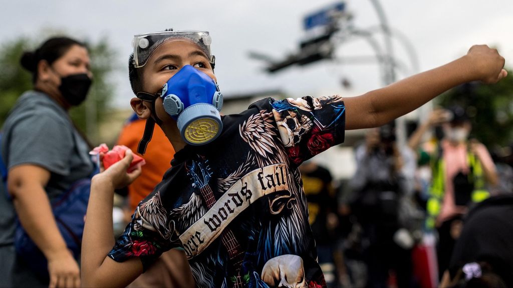 Seorang pengunjuk rasa melemparkan paket berisi cat merah ke polisi selama demonstrasi di Bangkok pada 27 September 2021, ketika para aktivis menyerukan pengunduran diri Perdana Menteri Thailand Prayut Chan-O-Cha atas penanganan pemerintah terhadap Covid -19.