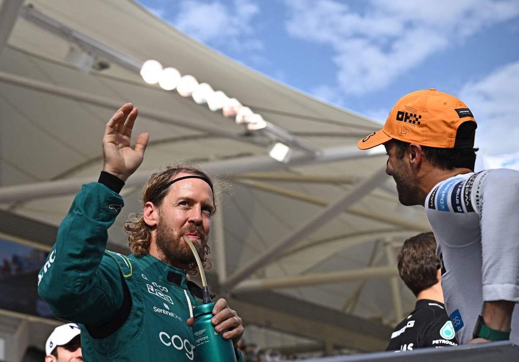 Pebalap Aston Martin, Sebastian Vettel (kiri), membalas sambutan penonton, disaksikan pebalap McLaren, Daniel Ricciardo (kanan), saat mengikuti parade pebalap jelang Grand Prix Formula 1 Abu Dhabi di Sirkuit Yas Marina, Uni Emirat Arab, Minggu (20/11/2022).