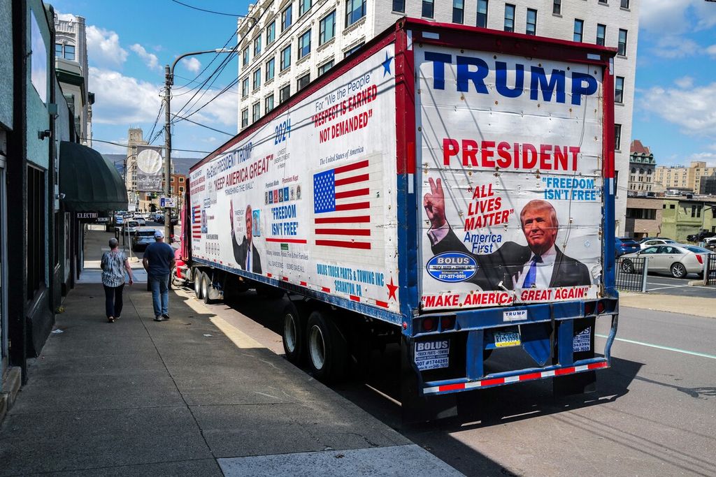 Pejalan kaki berjalan melewati truk yang mengiklankan mantan Presiden AS Donald Trump di Pennsylvania, 15 April 2024. 