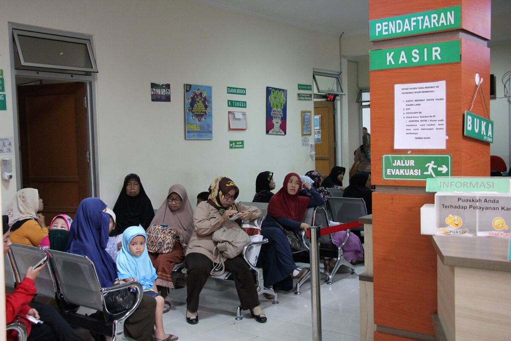 Warga duduk mengantre untuk berobat di Puskesmas Ciomas, Kabupaten Bogor, Jawa Barat, beberapa waktu lalu. Guna menekan angka rujukan ke rumah sakit, puskesmas terus didorong agar meningkatkan program promotif dan preventif.