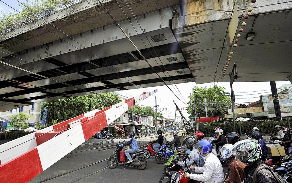 Pengendara sepeda motor menunggu kereta melintas di pelintasan kereta di bawah Jalan Layang Roxy, Jakarta Pusat, beberapa waktu lalu. 