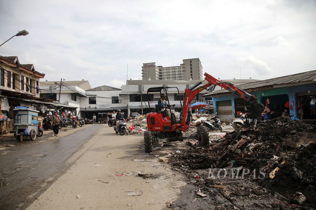 Alat berat digunakan untuk membersihkan lumpur di selokan dan sisa-sisa gusuran pedagang kaki lima di Jalan Haji Usman, sekitar Pasar Ciputat, Tangerang Selatan, Minggu (26/2/2023). 