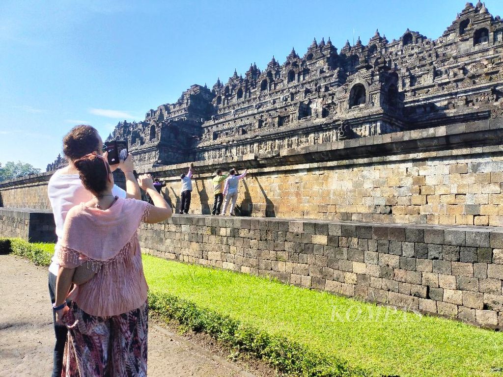 Dua wisatawan asing melihat aktivitas petugas yang membersihkan batuan Candi Borobudur, Kabupaten Magelang, Jawa Tengah, Selasa (14/6/2022)