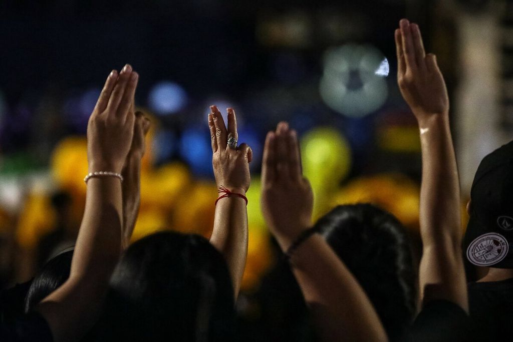 Pengunjuk rasa pro-demokrasi memberi salam tiga jari saat mereka mengambil bagian dalam unjuk rasa di depan pangkalan militer Resimen Infanteri ke-11 di Bangkok, Thailand, Minggu (29/11/2020). AFP/jACK TAYLOR