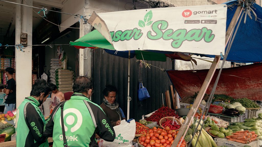 Ojek daring Gojek mengambil pesanan sayuran menggunakan aplikasi GoMart di Pasar Perumnas Klender, Jakarta Timur, Jumat (25/2/2022). Total nilai barang dagangan dari layanan pengiriman makanan meningkat. Perusahaan penyedia jasa dalam ekosistem digital berlomba untuk memperlebar ceruk pasar. 