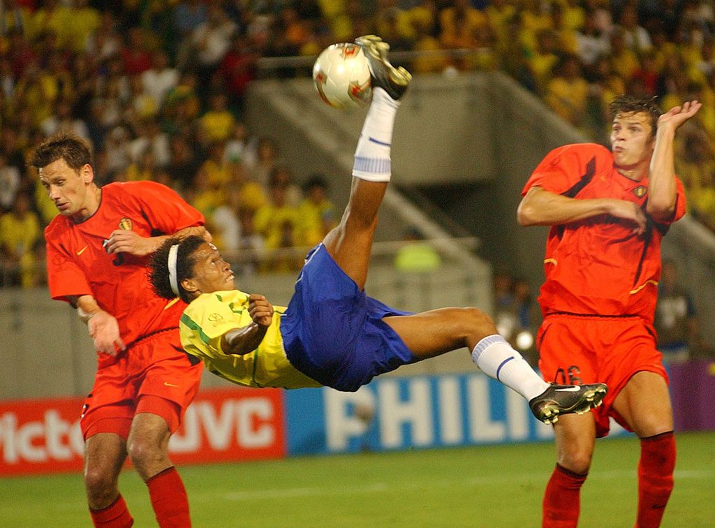 Pemain Brasil, Ronaldinho (tengah), melakukan tembakan salto pada Piala Dunia 2002 saat Brasil menghadapi Belgia di Stadion Kobe, Jepang, 17 Juni 2002. Kegemilangan Ronaldinho sudah tercium sejak tampil di Piala Dunia U-17 1997 di Mesir.