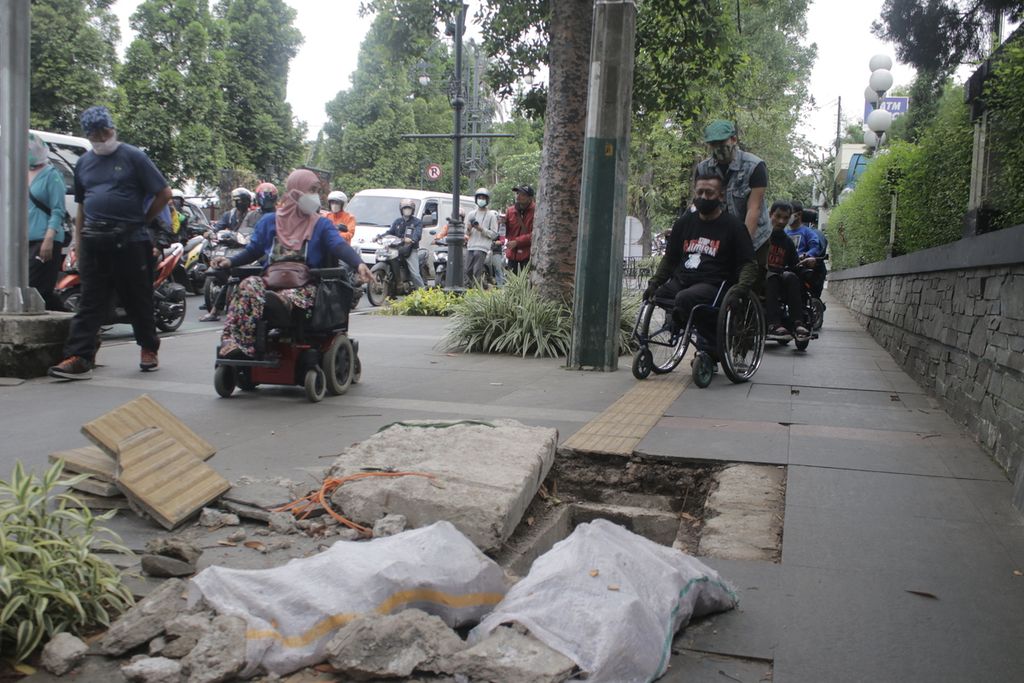 Pengguna kursi roda menghindari lubang di trotoar sisi Jalan Ir H Juanda atau Dago, Kota Bandung, Jawa Barat, Selasa (1/3/2022). Mereka kesulitan melintas di trotoar tersebut karena banyaknya lubang dan tidak rata.