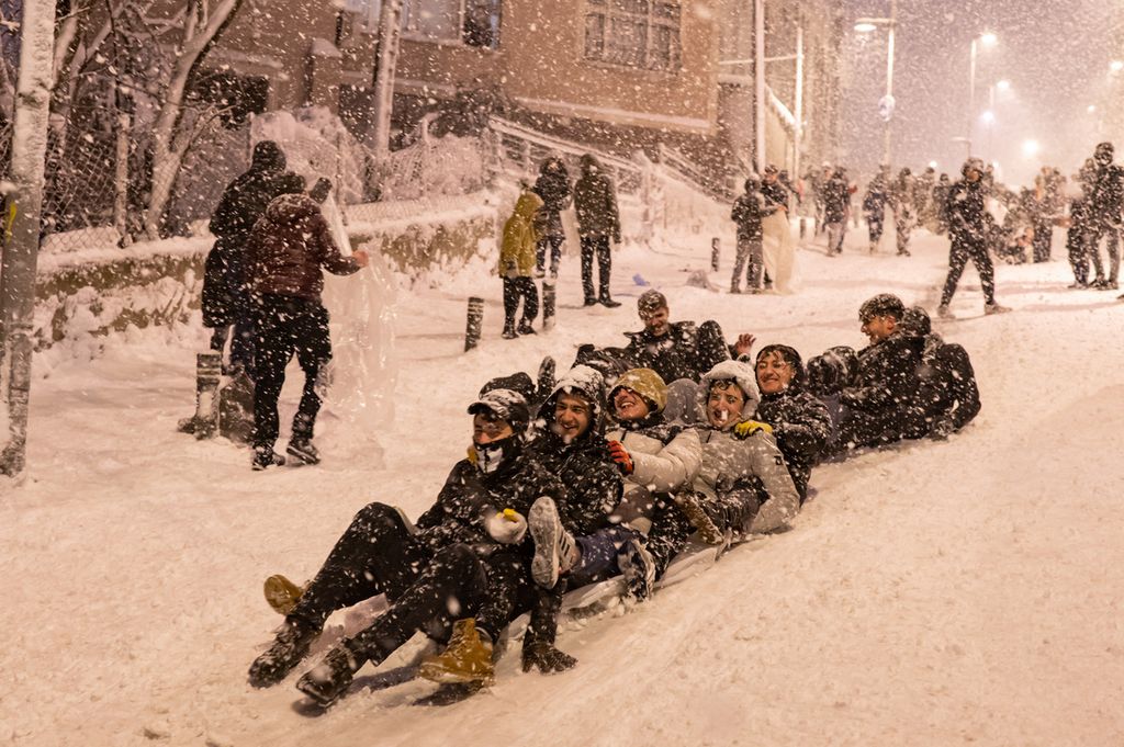 Anak-anak bermain seluncuran salju di Distrik Kucukcekmece di Istanbul, 24 Januari 2022. 