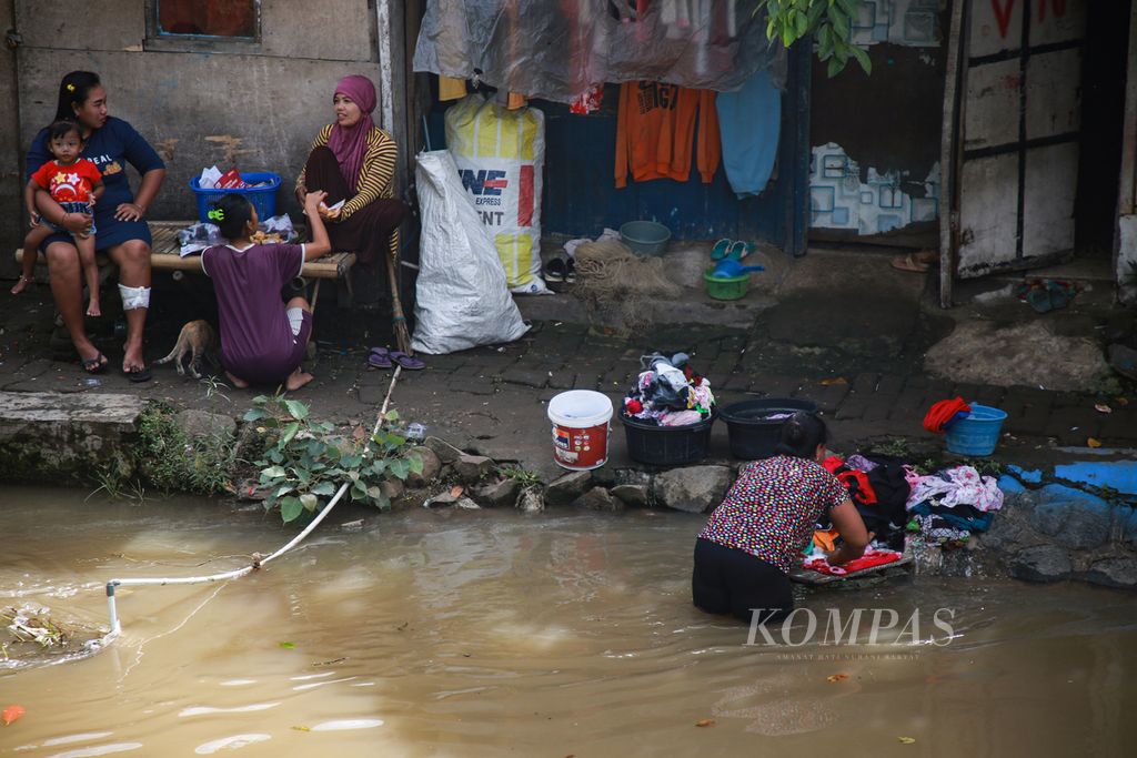 Warga mencuci pakaian di saluran air di Selapanjang Jaya, Kecamatan Neglasari, Kota Tangerang, Banten, Jumat (18/11/2022).
