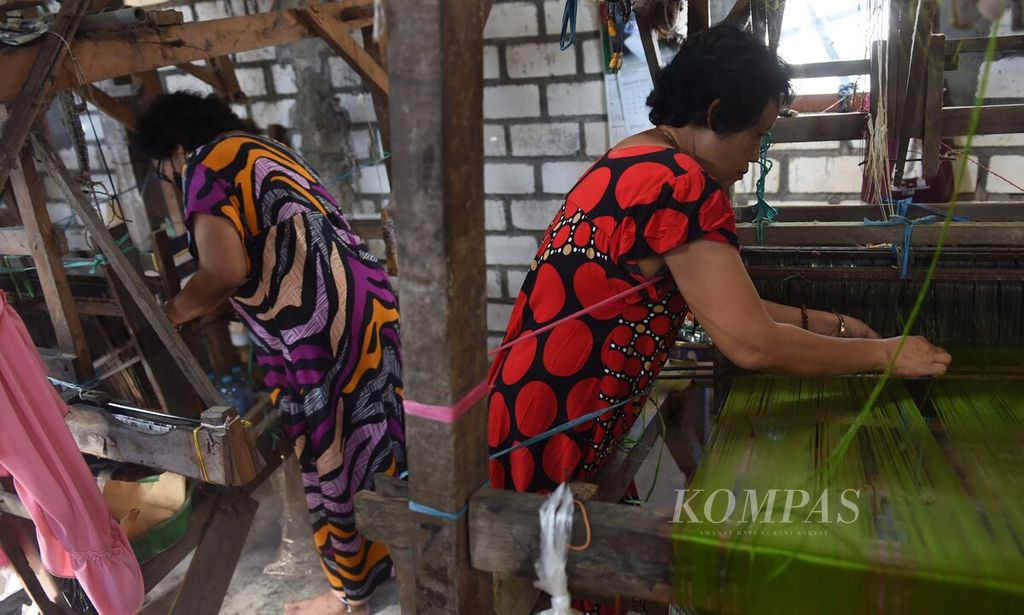 Perajin menyambung benang saat membuat sarung dengan alat tenun bukan mesin di Desa Iker-iker Geger, Kecamatan Cerme, Kabupaten Gresik, Jawa Timur, Rabu (22/6/2022). Sebagian besar pekerja adalah ibu rumah tangga sehingga waktunya dibagi antara mengurus keluarga dan membuat tenun. 