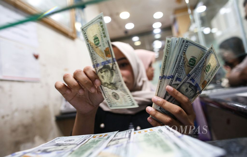 Petugas menghitung uang dollar AS di tempat penukaran valuta asing di Jakarta, Rabu (26/6/2024). 