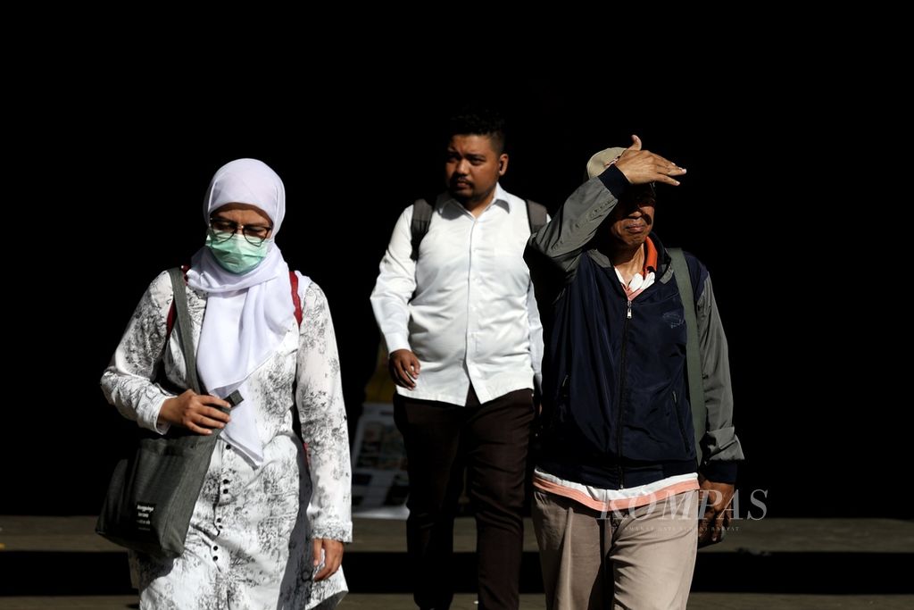A resident shields their face from the sun while walking in the Dukuh Atas area of Jakarta on Wednesday (20/3/2024).