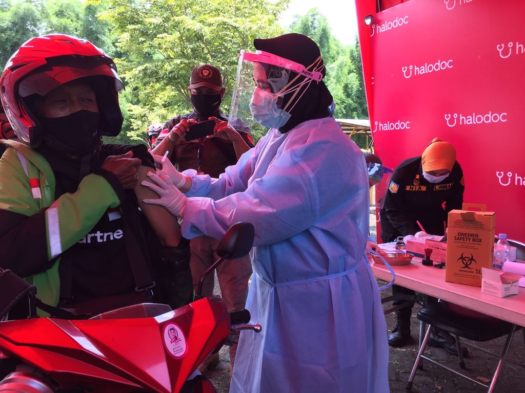 Pengojek sepeda motor menerima vaksinasi AstraZeneca melalui layanan tanpa turun (<i>drive thru</i>) di Universitas Surabaya, Surabaya, Jawa Timur, Sabtu (27/3/2021).