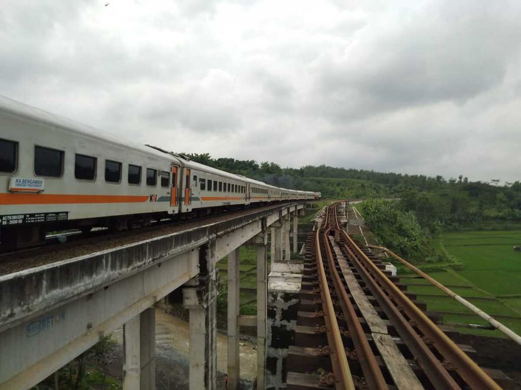 Kereta api melintas dengan kecepatan 20 kilometer per jam di salah satu jembatan di Desa Tonjong, Brebes, Jawa Tengah, Selasa (12/1/2021) siang. Jembatan di sebelahnya (kanan) ambrol akibat tergerus aliran sungai.