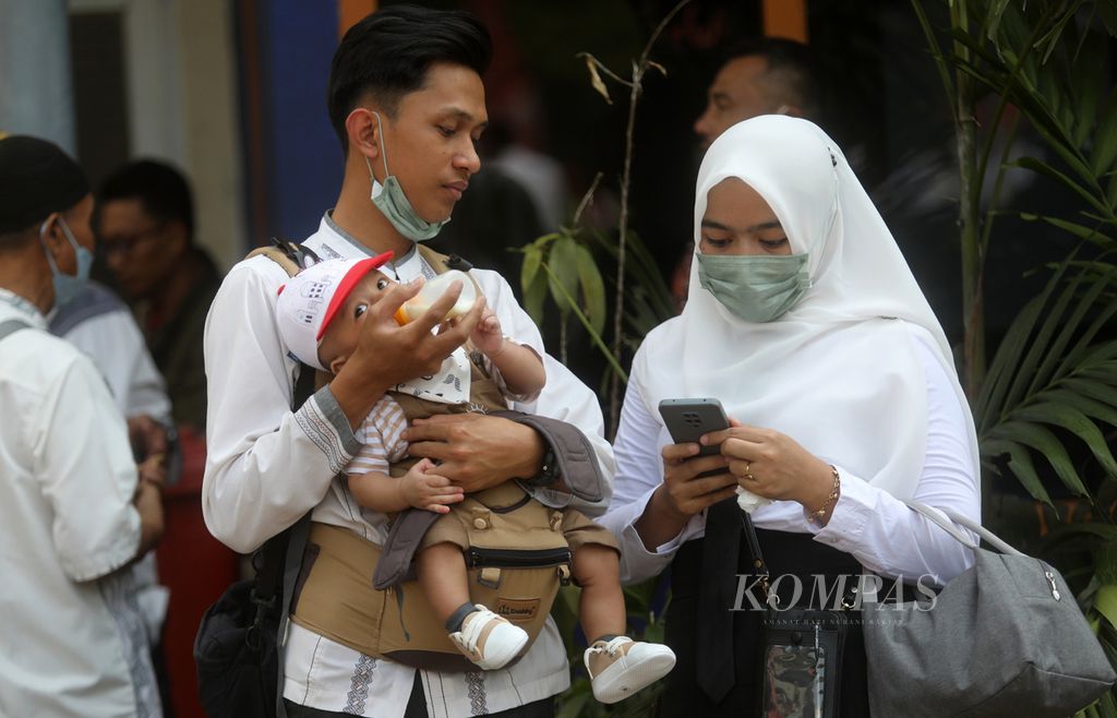 A husband of a honorary teacher carries his child after an inauguration ceremony in the courtyard of the Jakarta City Hall, Gambir, Central Jakarta, at the end of July 2023.