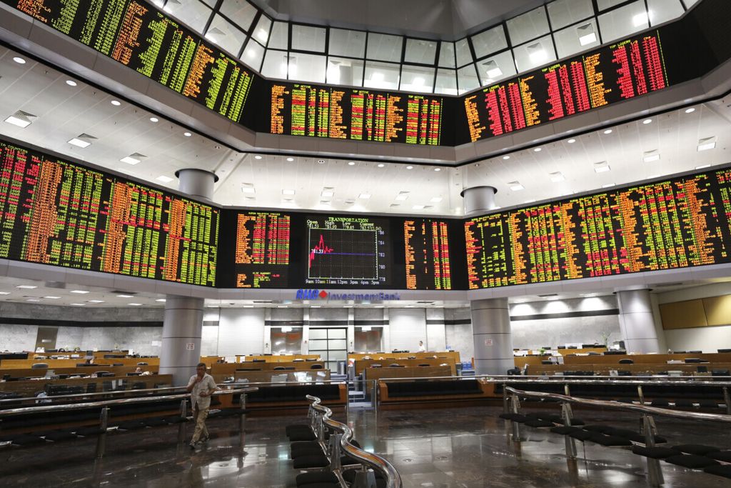 Seorang investor berjalan di depan papan perdagangan saham di sebuah galeri pasar saham swasta di Kuala Lumpur, Malaysia, pada 29 Juli 2019. 
