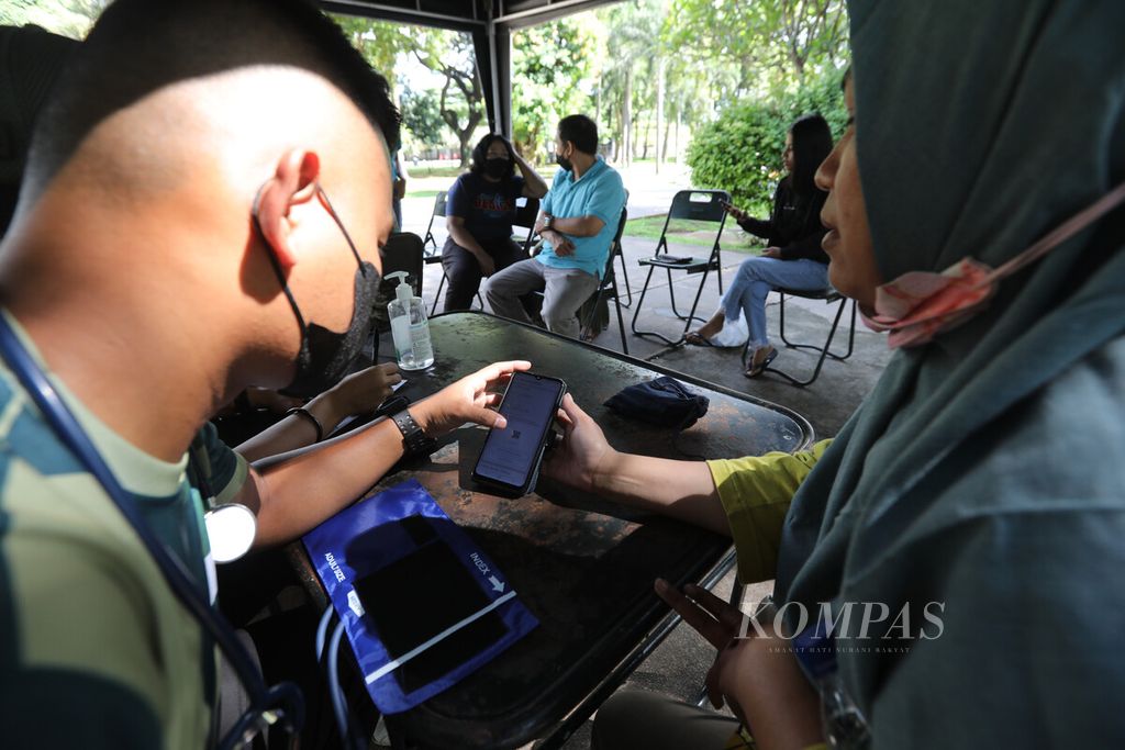 An officer from the Health Section of the Military District Command (Kodam) Jaya examined the Covid-19 vaccination ticket in the protected peduli application at the Banteng Field Park, Jakarta, Friday (6/1/2023).