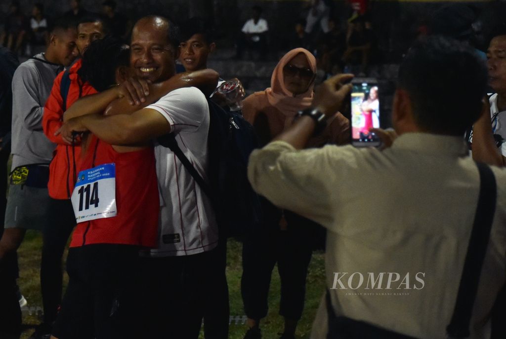 Pelari Bangka Belitung, Robi Syianturi, berpelukan dengan kerabatnya usai finis pertama perlombaan lari 10.000 meter senior putra Kejuaraan Nasional Atletik 2023 di Stadion Sriwedari, Solo, Jawa Tengah, Sabtu (24/6/2023). Robi Syianturi meraih emas dengan waktu 29 menit 59,47 detik. 