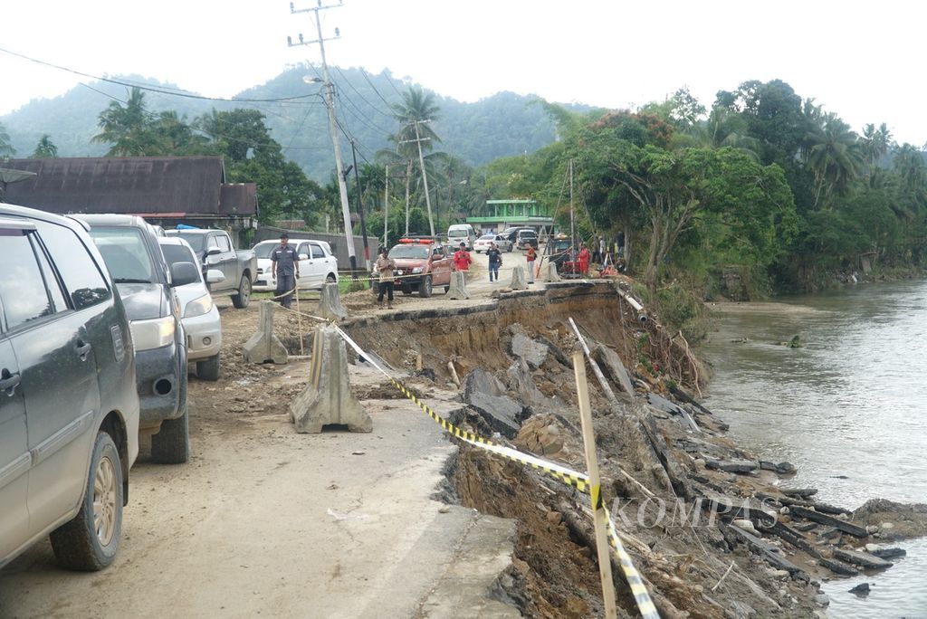 Kendaraan melintasi jalan terban akibat banjir di Nagari Barung-Barung Balantai, Kecamatan Koto XI Tarusan, Kabupaten Pesisir Selatan, Sumatera Barat, Senin (11/3/2024). 