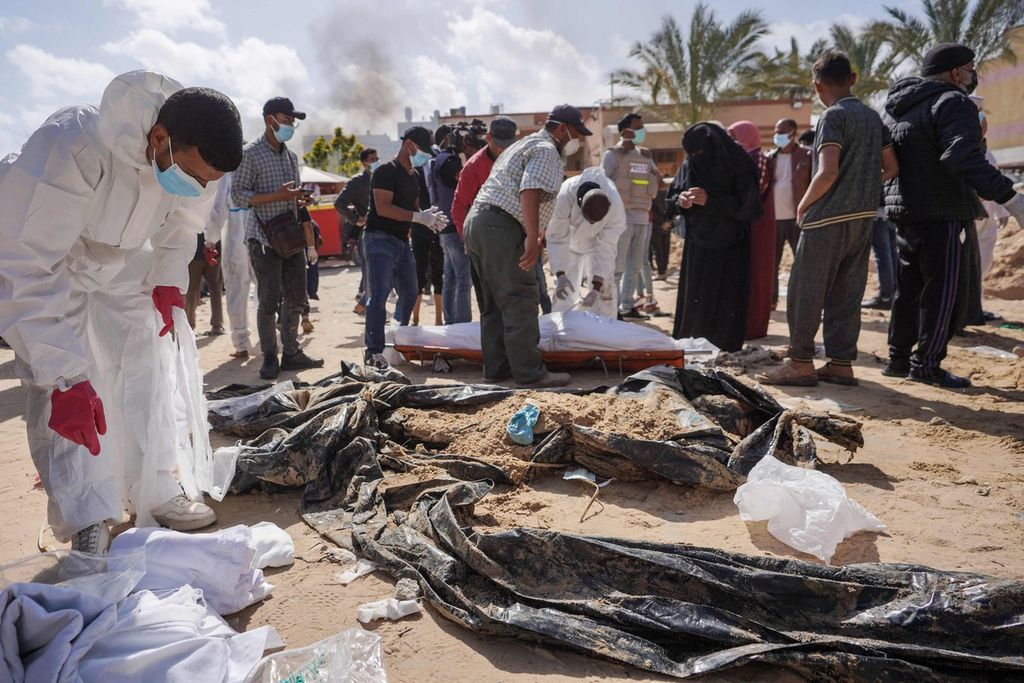Palestinian health officials stand at a mass grave discovered at the Nasser hospital complex in Khan Younis in southern Gaza Strip on April 21, 2024.