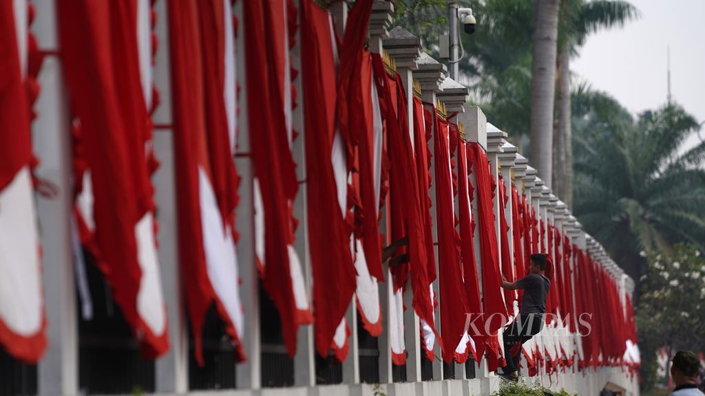 Pekerja memasang umbul-umbul gelombang merah putih di pagar Gedung DPR RI, Jakarta, Kamis (27/7/2023). 