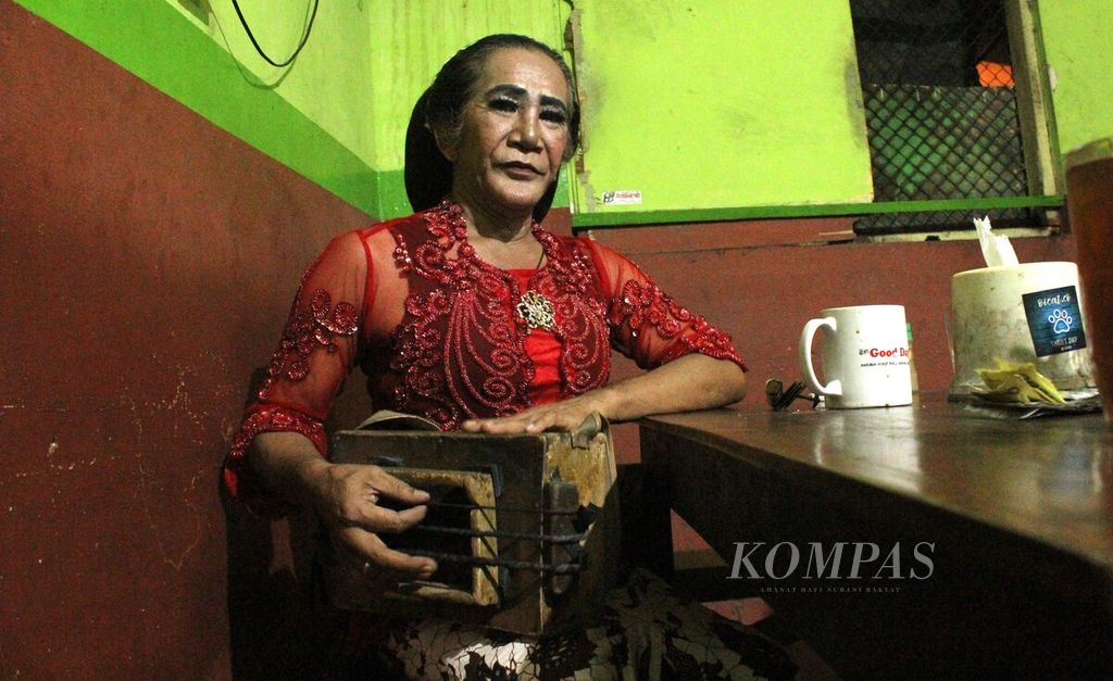 Transpuan pengamen, Eyang Erna (70), menunjukkan cara bermain bas betot kotak yang digunakan saat mengamen di warung-warung di bawah Jembatan Layang Janti, DI Yogyakarta, Rabu (20/7/2022) malam. Sudah lebih dari 25 tahun ia mengamen di Yogyakarta.