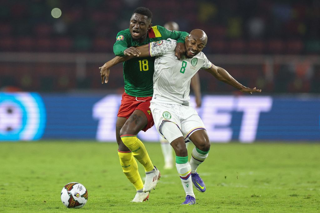 Gelandang Kamerun, Martin Hongla (kiri), berduel memperebutkan bola dengan gelandang Komoro, Fouad Bachirou, pada laga babak 16 besar Piala Afrika 2021, Selasa (25/2/2022) dini hari WIB, di Stadion Stadion Paul Biya, Kamerun. Pada laga itu, Kamerun menang 2-1 untuk melanju ke babak perempat final.