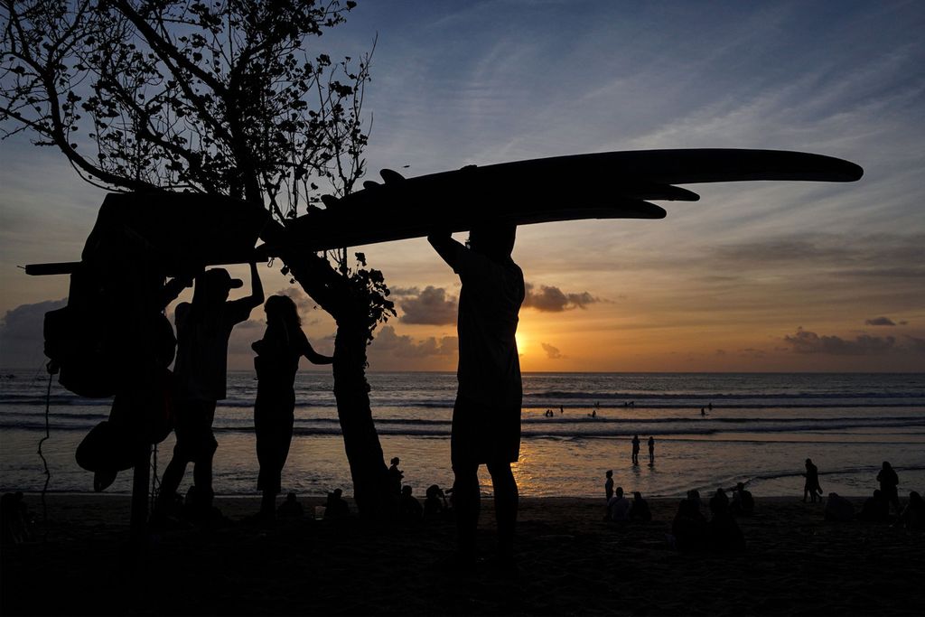 Petugas penyewaan papan selancar (<i>surfing</i>) mengemasi papan selancar di Pantai Kuta, Bali, Senin (11/10/2021). 