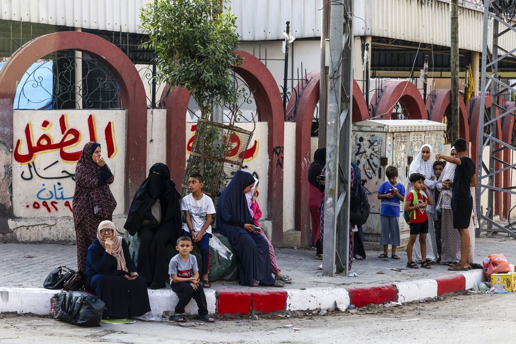Keluarga Palestina menunggu di jalan setelah meninggalkan rumah mereka di kota Gaza, Minggu (8/10/2023). Jumlah korban tewas melonjak menjadi hampir 1.000 sejak kelompok pejuang Palestina, Hamas, melancarkan serangan besar-besaran serangan terhadap Israel pada 7 Oktober 2023. 