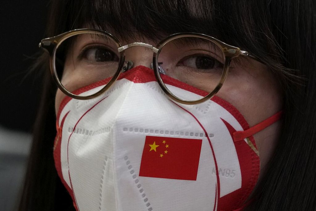 Seorang jurnalis memakai masker dengan gambar bendera China bersimbol bintang lima di Taman Shougang, Beijing, China, Jumat (21/1/2022). 