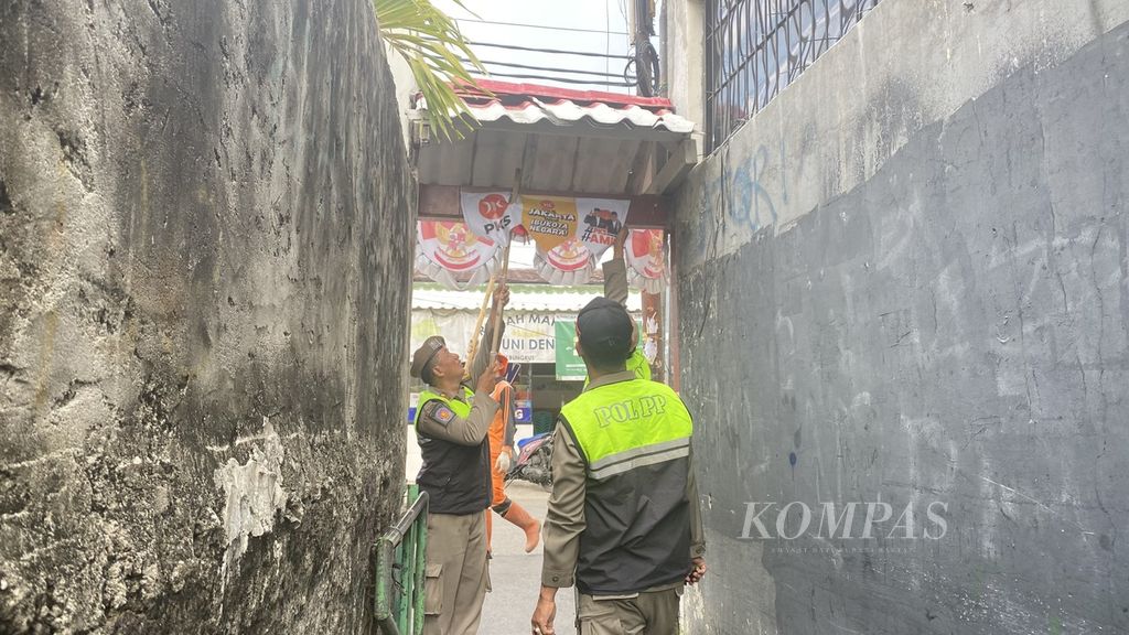 Satuan Polisi Pamong Praja DKI Jakarta menurunkan alat peraga kampanye di Petamburan, Jakarta Pusat, Minggu (11/2/2024).
