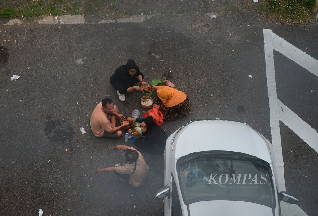 Keluarga pemudik yang membuka bekal makanan mereka di tengah kepadatan arus balik kendaraan yang melintasi di Jalan Tol Bawen-Semarang, Ungaran, Kabupaten Semarang, Jawa Tengah, Jumat (6/5/2022). 