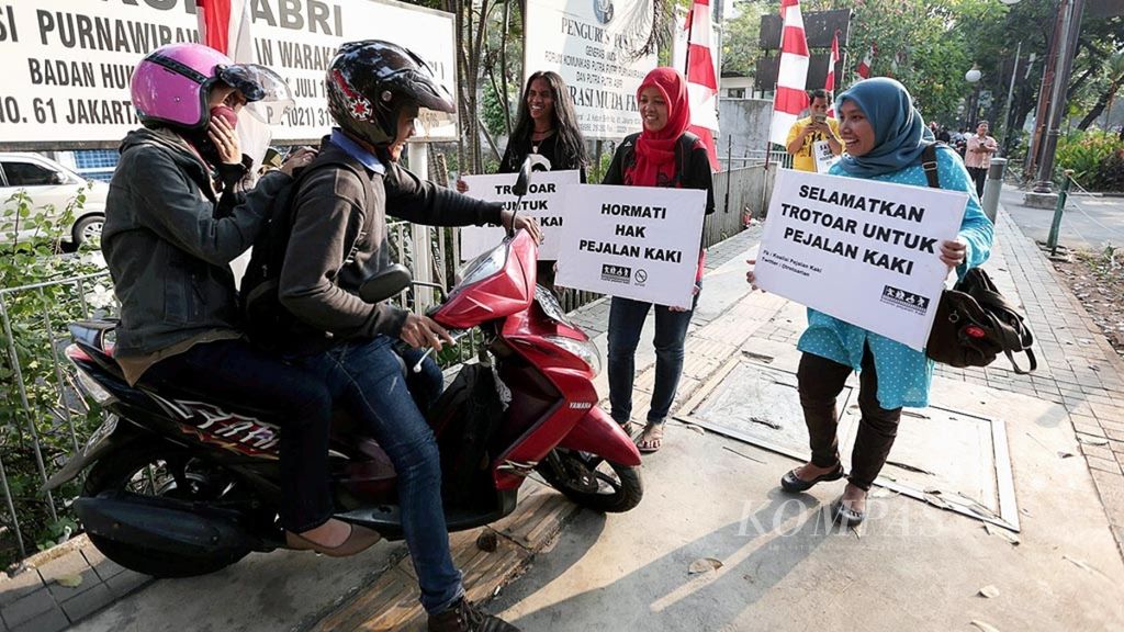 Warga yang tergabung dalam Koalisi Pejalan Kaki menghalau pengendara sepeda motor yang melintas di trotoar di Jalan Kebon Sirih, Jakarta Pusat, Jumat (14/8). Aksi ”begal” pemotor di trotoar itu sebagai upaya pejalan kaki mencari kemerdekaan 100 persen di trotoar,<i> zebra cross</i>, dan jembatan penyeberangan orang (JPO) dari sepeda motor, pedagang kaki lima yang berjualan di trotoar dan JPO, serta kendaraan yang parkir di trotoar.