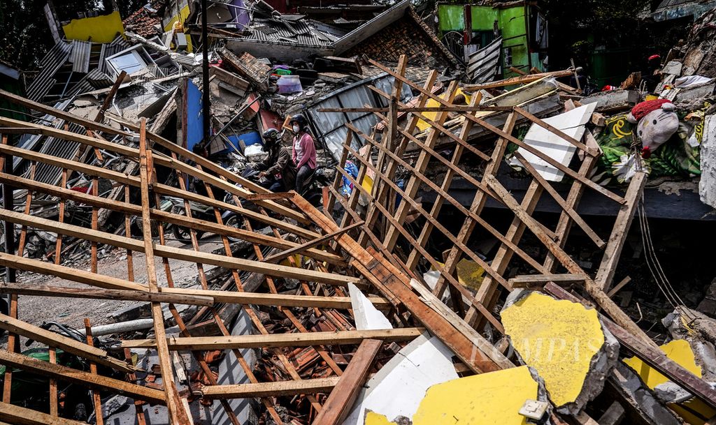 Warga melintasi reruntuhan di Desa Gasol, Cugenang, Kabupaten Cianjur, Jawa Barat, Selasa (22/11/2022). Kondisi kerusakan akibat gempa yang melanda Cianjur pada Senin (22/11/2022) terlihat di sejumlah wilayah desa yang terdampak. 