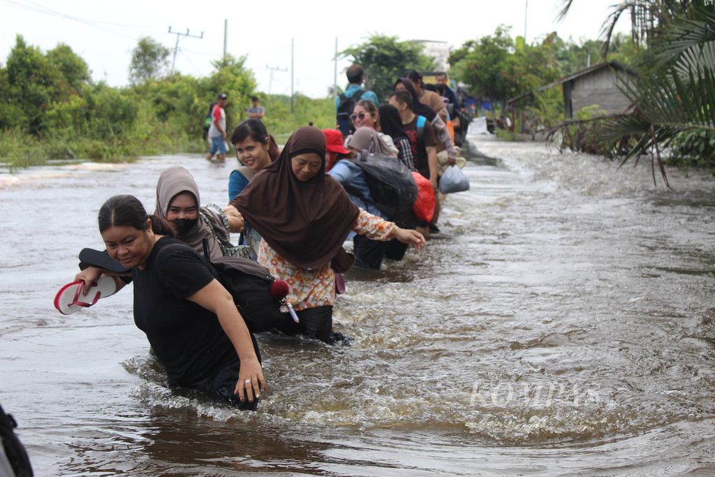 Beberapa petugas puskesmas beserta dokter dan tenaga kesehatan lainnya melintasi banjir di Desa Lembeng, Kecamatan Dusun Selatan, Kabupaten Barito Selatan, Kalteng, pada Kamis (25/1/2024). Banjir memutus sementara akses Trans-Kalimantan yang menghubungkan tiga provinsi itu.