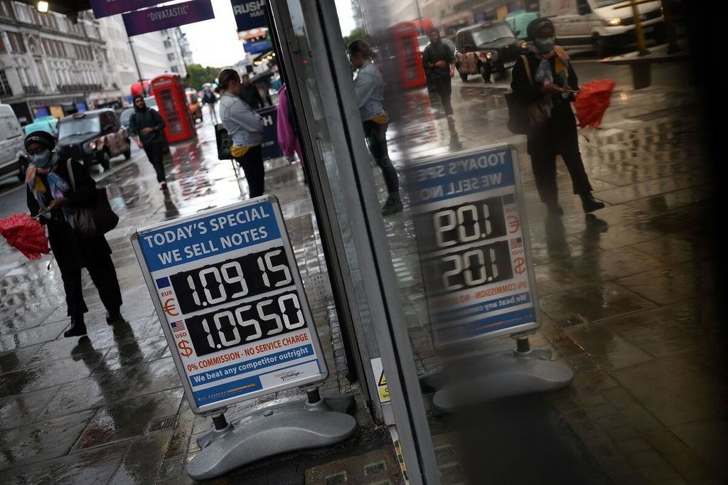 Warga berjalan melewati papan yang memasang nilai tukar mata uang euro dan dollar AS terhadap poundsterling di luar tempat penukaran mata uang di pusat kota London, Inggris, 27 September 2012. 