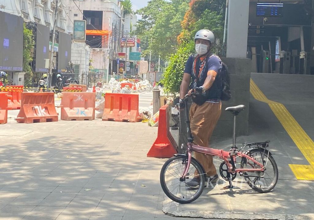 Seorang warga membawa sepeda lipat saat keluar dari Stasiun Sudirman, Jakarta Pusat, Rabu (11/10/2023).