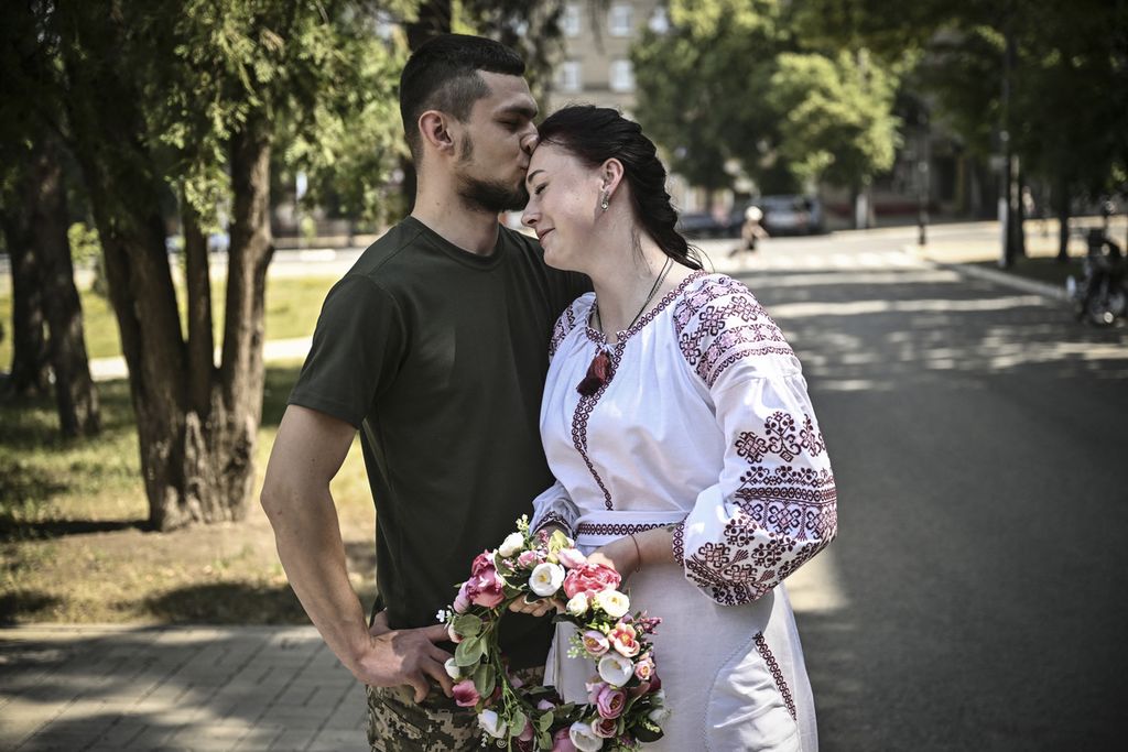 Kristina (kanan) dan Vitaliy Orlich, keduanya tentara Ukraina yang aktif bertugas, menikah di kota Druzhkivka, wilayah Donbas, Ukraina timur, 12 Juni 2022. 