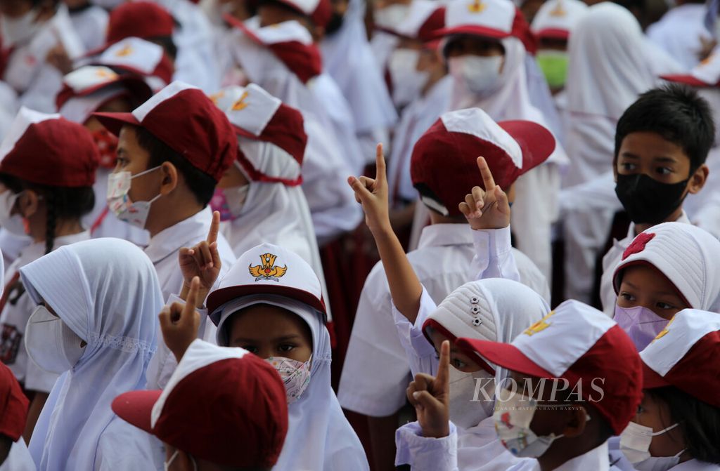 Anak-anak mengangkat jarinya saat berkumpul di lapangan pada hari pertama sekolah tahun ajaran baru 2022/2023 di SD Negeri 11 Pondok Bambu, Jakarta, Senin (11/7/2022). 
