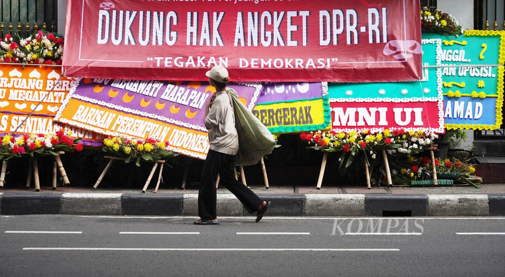 Pemulung melintas di depan Kantor DPP PDI Perjuangan di Jalan Diponegoro, Jakarta, yang dipenuhi karangan bunga dan spanduk desakan penggunaan hak angket oleh PDI-P, Jumat (8/3/2024). 