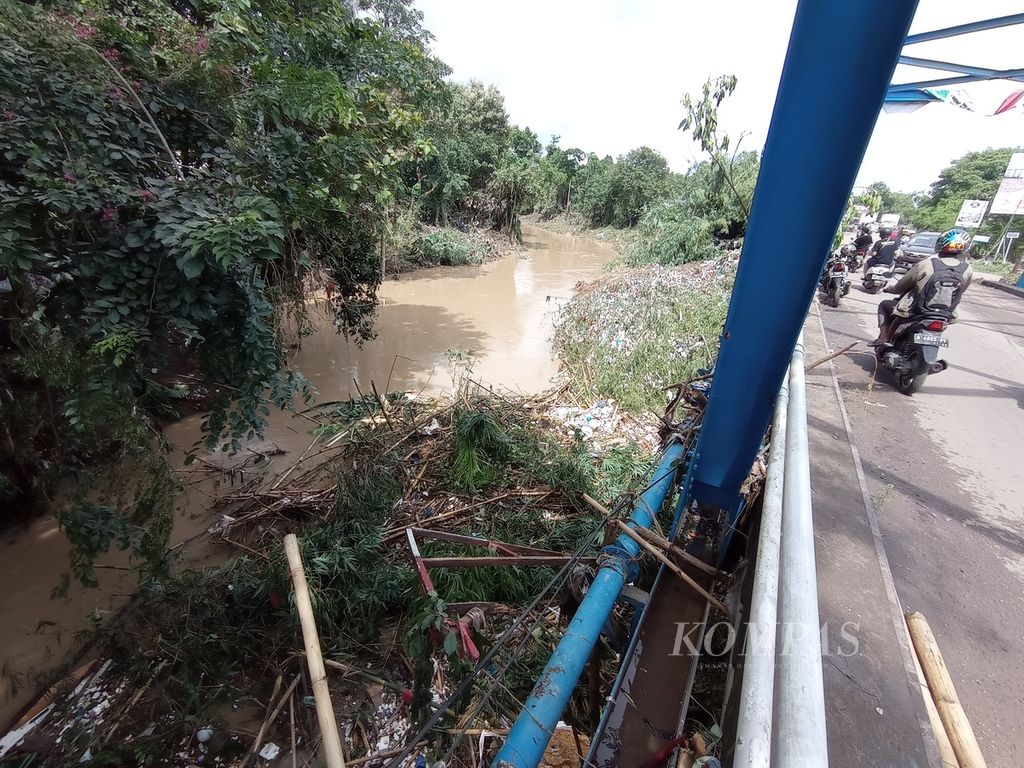 Material yang tersapu banjir tersangkut di jembatan penyeberangan di dekat Jalan Tol Serang-Merak, Kota Serang, Banten, Rabu (2/3/2022).