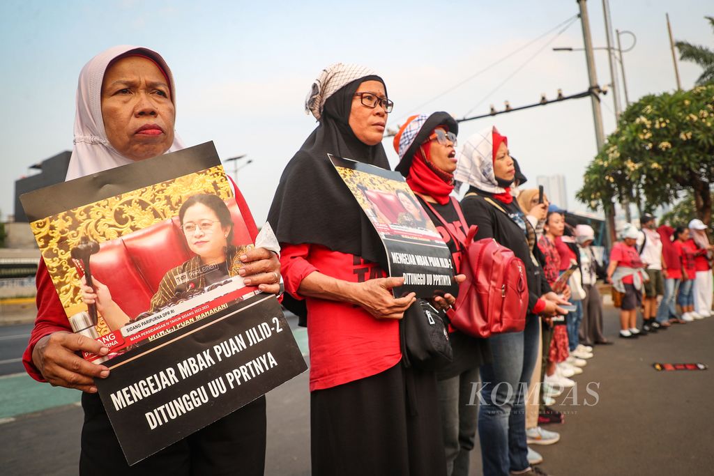 Peserta aksi menyanyikan lagu "Darah Juang" sembari membawa poster tuntutan dalam acara peluncuran film <i>Mengejar Mbak Puan</i> di depan Gedung DPR, Jakarta, Kamis (12/10/2023).  